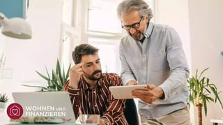 Zwei Männer vergleichen Zinsen am Tablet