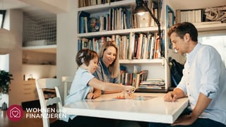 Familie sitzt an Tisch im Eigenheim