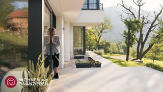 Frau schaut aus Terrassentür eines Hauses