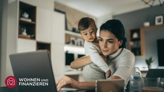 Frau sucht mit ihrem Baby auf dem Arm nach Häusern im Internet