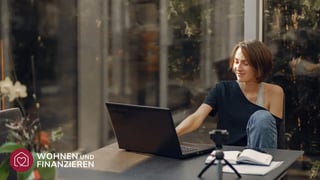 Frau recherchiert am Laptop wie viel Baukredit sie sich leisten kann